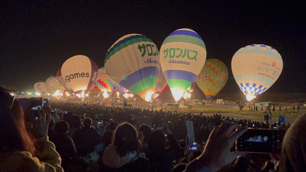 Approximately three-dozen balloons at night lighting their flames as part of La Montgolfier Nocturne (Night Mooring) at the Saga International Balloon Fiesta.